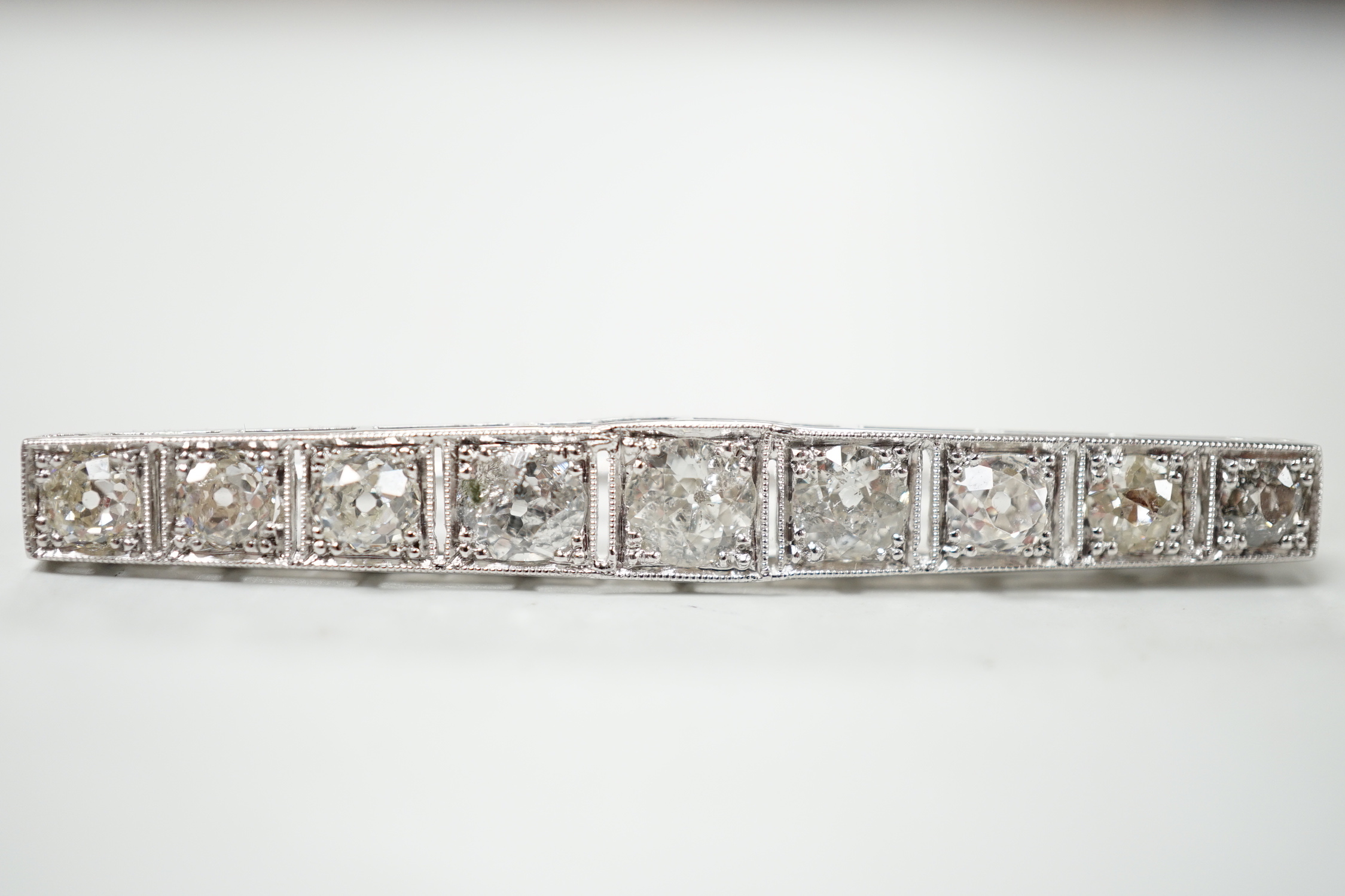 A 1920's/1930's white metal and graduated nine stone diamond set bar brooch, 48mm, gross weight 4.6 grams.